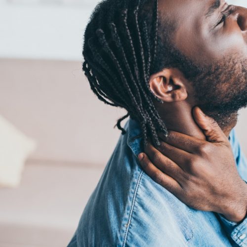 handsome african american man suffering from neck pain with closed eyes